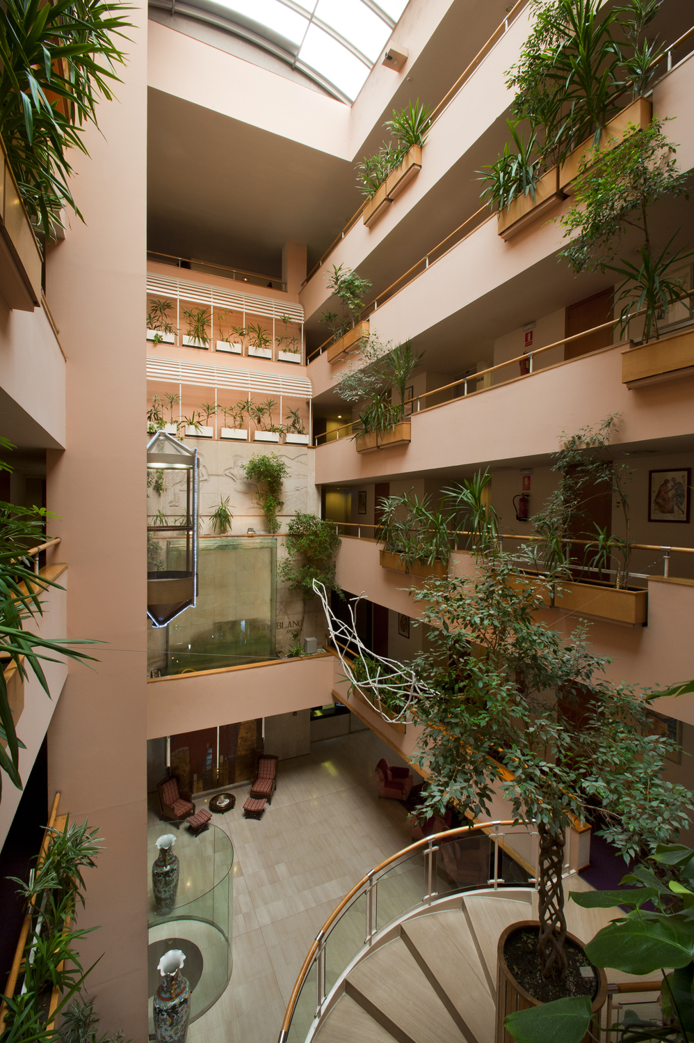 hall of the hotel with view on different floors, elevator, stairs and plants - Hotel Roc Blanc