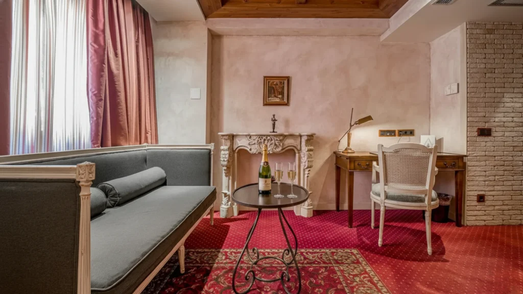 A bottle of sparkling wine with two glasses on the table in the room of the romantic getaway at the Roc Blanc Andorra hotel